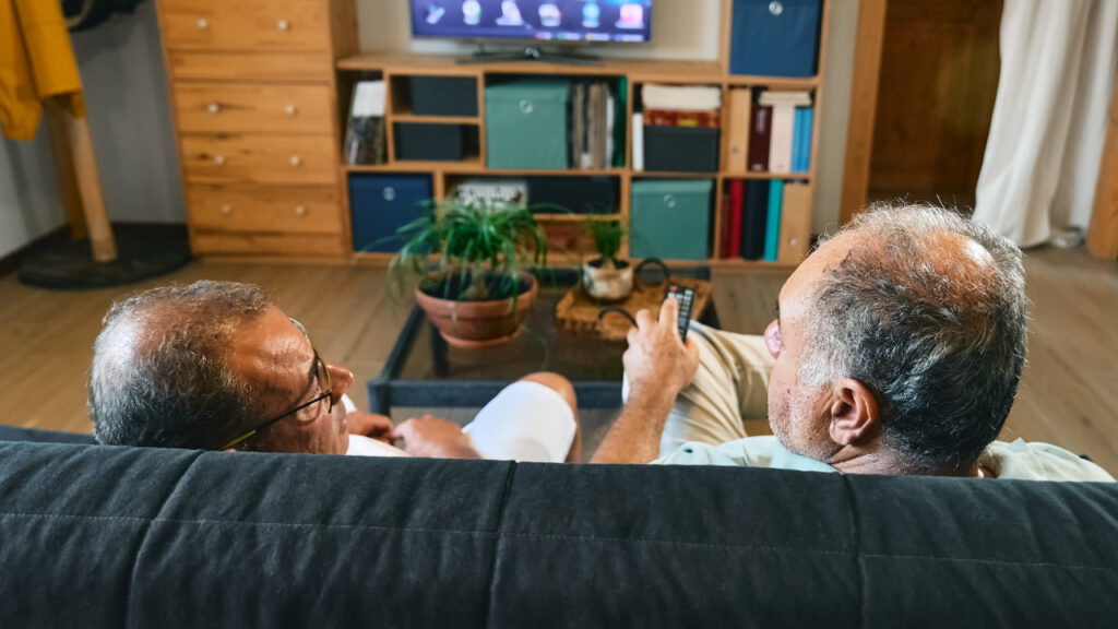 two older people sitting facing the television