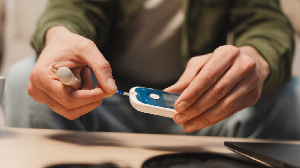 A man carrying out a blood sugar test on the meter
