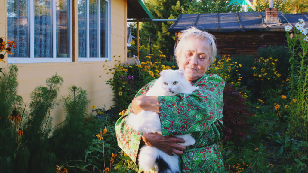 Older lady in her garden with a cat on her lap