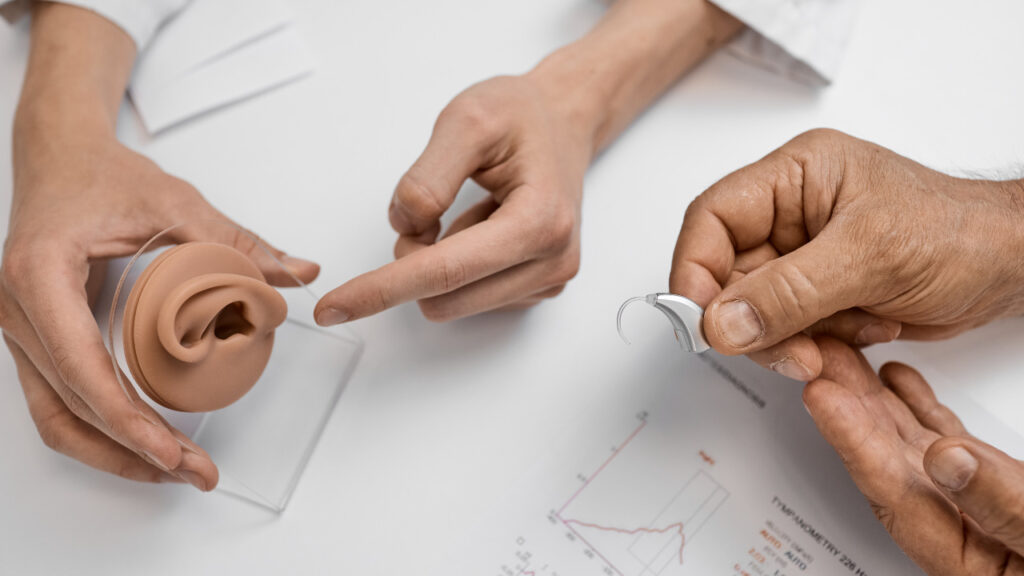 the doctor's hands holding the aid and explaining to the older person how it works