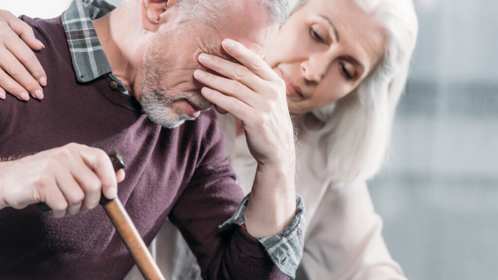 Man with Alzheimer's feeling sad but receiving support from a carer